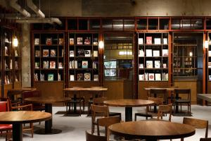 a restaurant with wooden tables and chairs and bookshelves at Matsumoto Jujo in Matsumoto