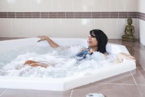 Eine Frau sitzt in einer Badewanne in der Unterkunft Vacancéole - Le Domaine des Grands Lacs in Parentis-en-Born