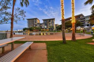 a park with a bench and palm trees and buildings at Darwin's Dazzler - Your Ultimate Waterfront Escape in Darwin