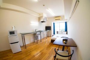 a room with a bed and a kitchen with a table at S-Presso Namba Parks Street in Osaka