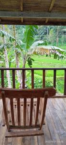 eine Holzbank auf einer Veranda mit einer Palme in der Unterkunft Ranggon d'tukad in Tabanan