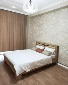 a bedroom with a large white bed and a chandelier at Престижная квартира Кара Караева in Baku