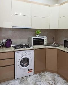 a kitchen with a washing machine and a microwave at Престижная квартира Кара Караева in Baku