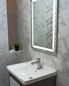 a white bathroom with a sink and a mirror at Престижная квартира Кара Караева in Baku