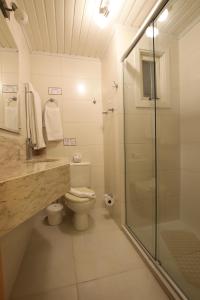 uma casa de banho com um WC e uma cabina de duche em vidro. em Pousada Águia Branca em Gramado