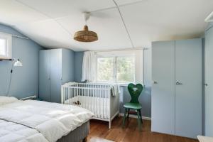 Skummeslövsstrand的住宿－Nice holiday home near Skummelovs strand，蓝色卧室配有婴儿床和绿色椅子