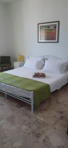 a white bed with a green blanket on top of it at Al Settimo Cielo Termoli in Termoli