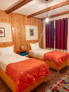 dwa łóżka w pokoju z drewnianymi panelami w obiekcie Guesthouse Lord Byron w mieście Tepelenë