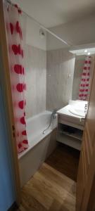 uma casa de banho com uma banheira, um lavatório e um espelho. em Charmant appartement de 6 pers tout confort em Puy-Saint-Vincent