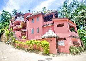 um edifício cor-de-rosa com uma palmeira à frente. em Signature Boracay Punta Rosa formerly Punta Rosa Boutique Hotel em Boracay