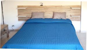 ein blaues Bett in einem Schlafzimmer mit einem Kopfteil aus Holz in der Unterkunft La Ninfa in Acitrezza