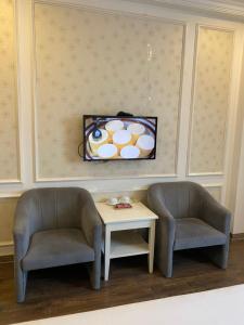 two chairs and a table and a tv on a wall at Khách Sạn A83Hotel in Hanoi