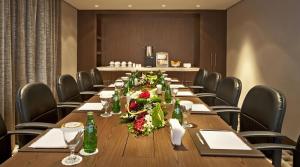 a conference room with a long table with flowers on it at Oaks Liwa Executive Suites in Abu Dhabi