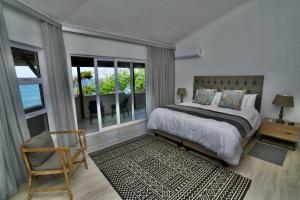 a bedroom with a bed and a chair and windows at Oceans Paradise in Ballito