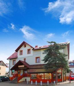 un grand bâtiment blanc avec un arbre en face dans l'établissement Gościniec Halka, à Zwardoń