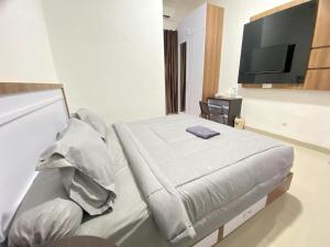 - une chambre avec un lit et une télévision à écran plat dans l'établissement MJ Guest House Pusat Kota Malili Mitra RedDoorz, à Malili