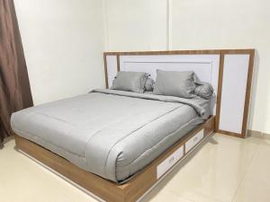 1 cama con marco de madera y almohadas en MJ Guest House Pusat Kota Malili Mitra RedDoorz en Malili