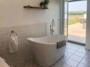 a white bath tub in a bathroom with a patio at The Old Dairy - Uk31253 in Middleton