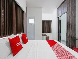 een groot wit bed met rode kussens erop bij Super OYO Capital O 91665 D'prof Exclusive Guesthouse in Semarang