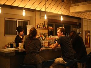TRAVEL&BOOK HOTEL HULATONCABIN TAKAMATSU في تاكاماتسو: مجموعة من الناس يجلسون في حانة