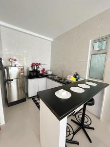 a kitchen with a black and white counter top at Aina Staycation, Metrocity in Kuching