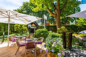 eine Terrasse mit lila Stühlen, Tischen und einem Sonnenschirm in der Unterkunft Hotel Mercator Itzehoe-Klosterforst in Itzehoe