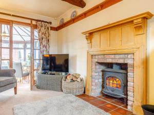 a living room with a fireplace and a tv at The Pigsty - Uk30945 in Barthomley