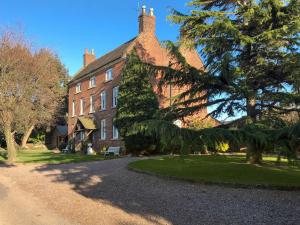 a large red brick house with a tree in front of it at The Pigsty - Uk30945 in Barthomley