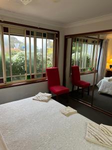 a bedroom with two red chairs and a bed and windows at JOHN HUNTER B&B in Lambton