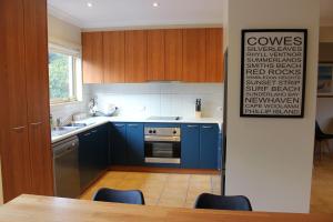 una cucina con armadi blu e tavolo con sedie di Beachside Haven at Cowes a Cowes