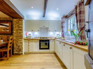 a kitchen with white cabinets and a table and a window at Kilcot Coach House in Hillsley