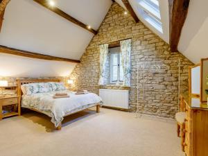 a bedroom with a bed and a stone wall at Kilcot Coach House in Hillsley