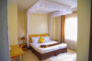 Un dormitorio con una cama grande con dosel. en Acacia Hotel Mbarara, en Mbarara