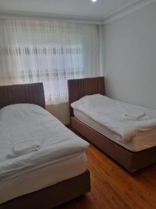 two twin beds in a room with a window at Erdem Apartment in Atakum