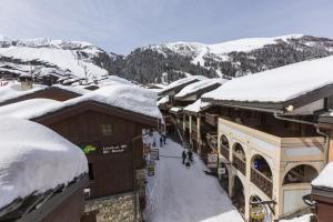 una città innevata con tetti e edifici coperti da neve di Hôtel du Bourg a Valmorel