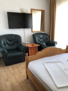 1 Schlafzimmer mit 2 Stühlen, einem Bett und einem Flachbild-TV in der Unterkunft Pensiune Roua 2 in Arad
