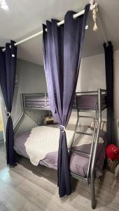 a bedroom with two bunk beds with purple curtains at Coquet et accueillant Studio montagne la Mongie in Bagnères-de-Bigorre