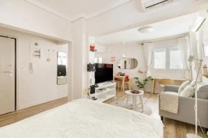 a white bedroom with a bed and a living room at Lovely small (parterre) apartment in Thessaloniki in Thessaloniki