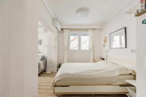 a white bedroom with a bed and a window at Lovely small (parterre) apartment in Thessaloniki in Thessaloniki