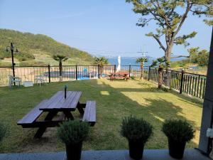 a picnic table in a yard with a view of the ocean at Secret Garden Pension in Yeosu