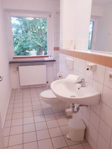 uma casa de banho branca com um lavatório e um WC em Christian Jensen Kolleg und Gästehäuser em Breklum