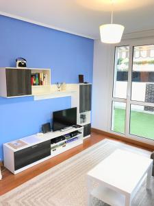 een woonkamer met een tv en een blauwe muur bij Apartamento Libertad in Castro-Urdiales