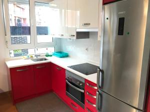 een keuken met rode kasten en een roestvrijstalen koelkast bij Apartamento Libertad in Castro-Urdiales