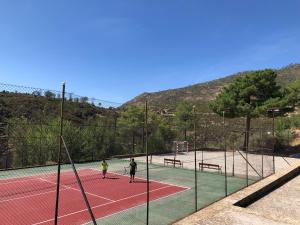 two people playing tennis on a tennis court at Casa Rural Los Olivos de Robledo de Chavela in La Estación