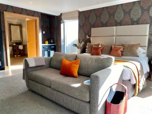 een slaapkamer met een bed en een bank met oranje kussens bij Alexander House Hotel & Utopia Spa in Turners Hill