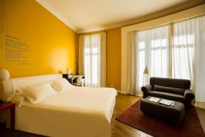 a bedroom with a white bed and a black chair at Iberostar Las Letras Gran Via in Madrid