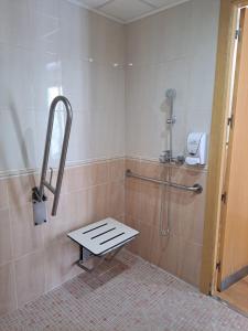 a shower stall with a bench in a bathroom at Hotel Plaza Inn in Figueres