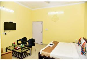 ein Hotelzimmer mit einem Bett und Stühlen sowie einem TV in der Unterkunft Samriddhi Stay Inn in Lucknow