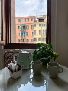 una mesa con dos tazas y una tetera y una ventana en Residenza San Silvestro, en Venecia