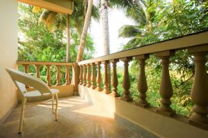 a balcony with a chair and palm trees at Casa Da Village Calangute Goa in Calangute